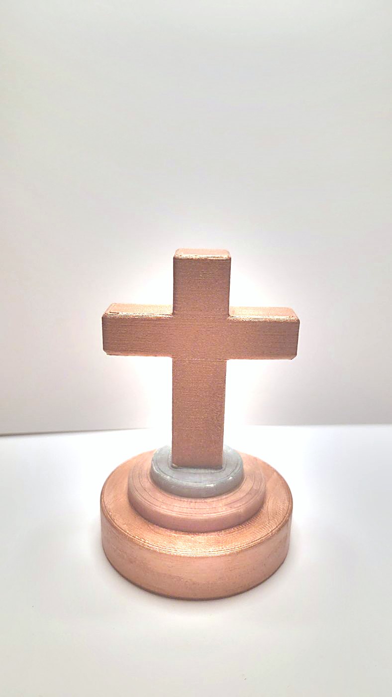 A cross painted copper on a wooden-look base