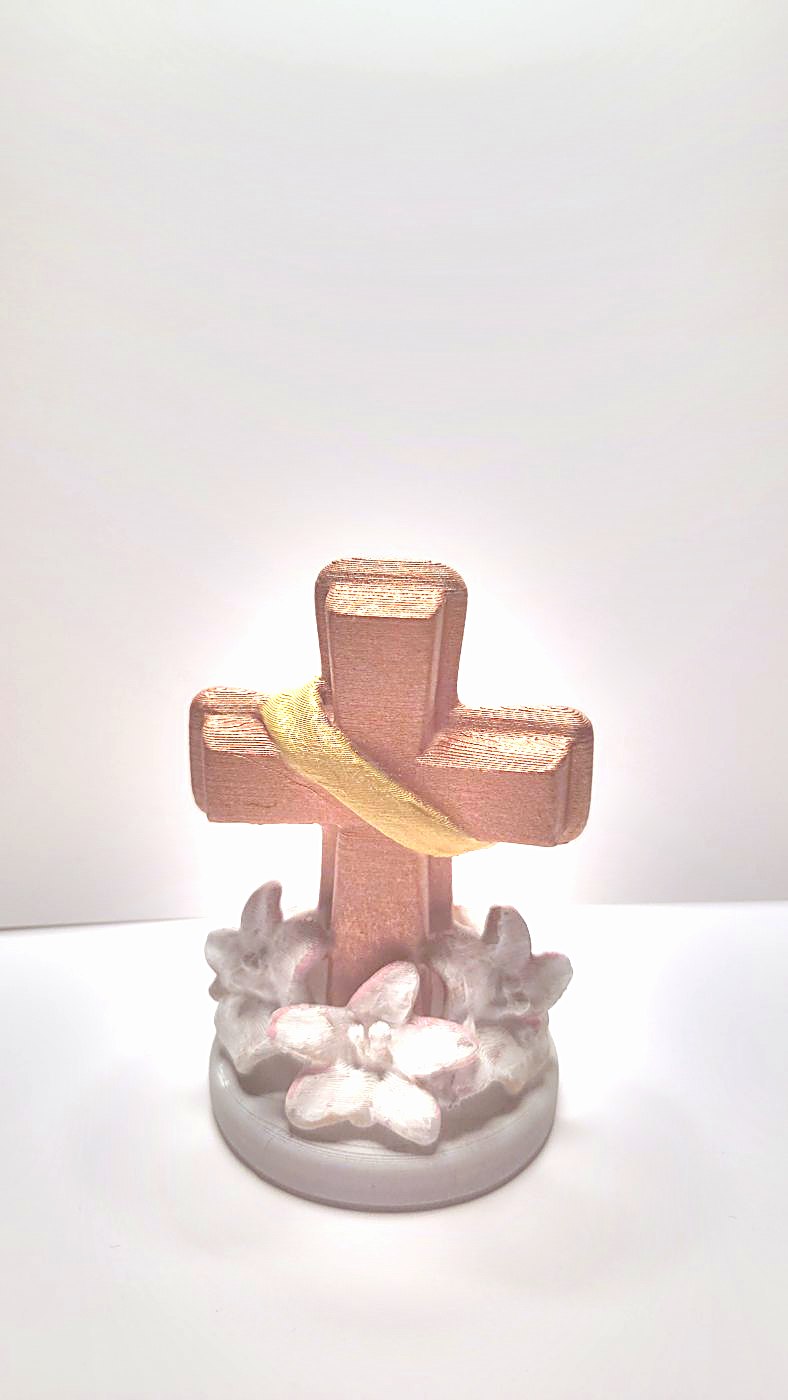 A painted cross with a gold sash and white flowers at its foot